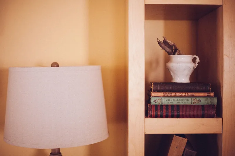 Mid-century modern solid-wood bookshelf with tapered splayed legs and warm walnut-tone finish, handcrafted in Jodhpur, India